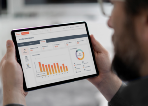 Man with a beard looking at a tablet that displays graphs titled Auction Dashboard